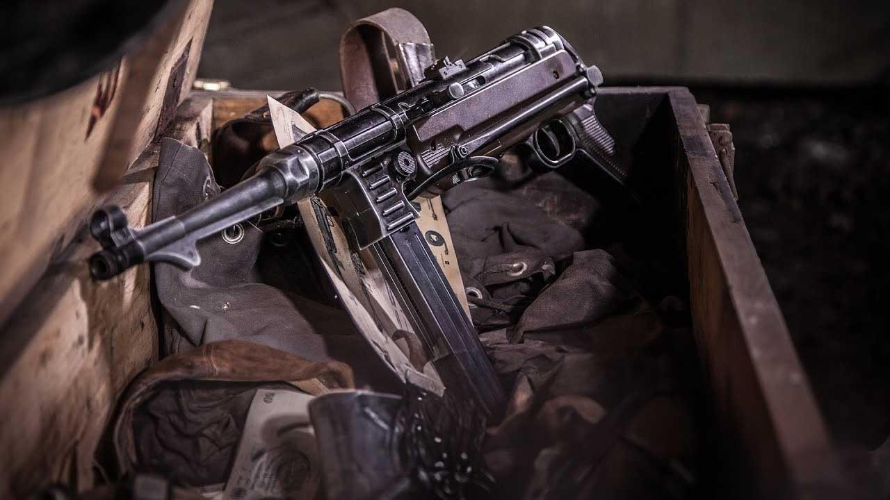 Umarex Legends MP German C02 BB Air Rifle 7 A Umarex Legends MP German CO2 BB Air Rifle sits atop military gear in a wooden crate, surrounded by fabric and leather accessories.