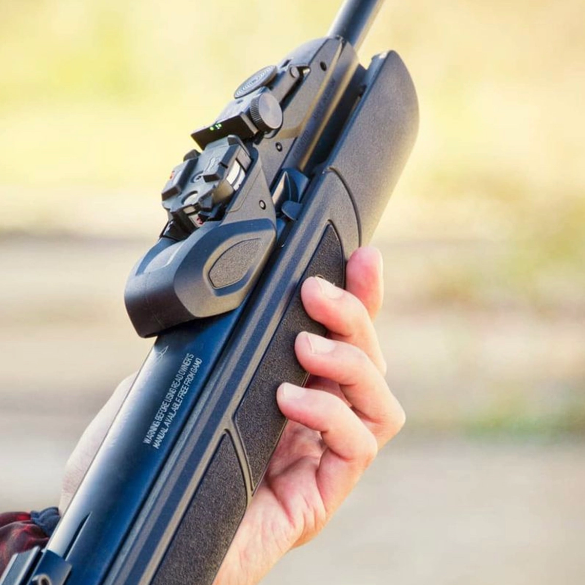 Gamo Swarm Speedster Gen 2 Multi Shot Spring Air Rifle With Scope 9 A person holds a Gamo Swarm Speedster Gen 2 Spring Air Rifle With Scope, gripping the stock with their right hand against a blurred outdoor background.