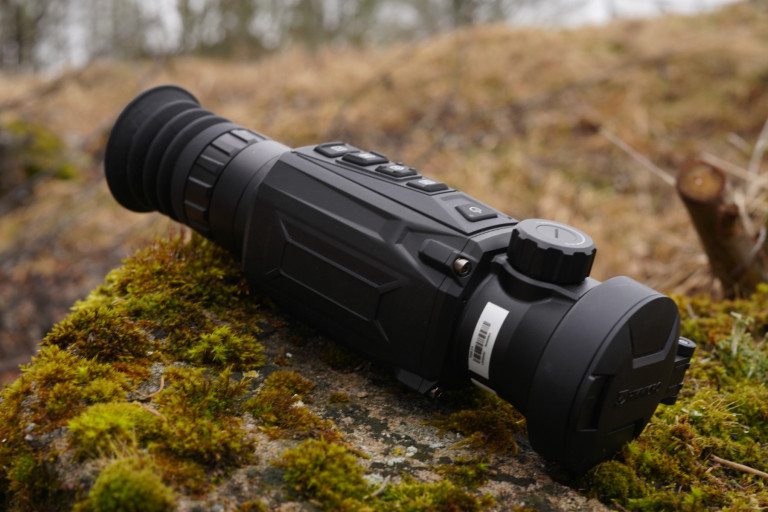 HIKMICRO Thunder 2.0 Pro TQ50 Smart Thermal Scope With Rail 11 A HIKMICRO Thunder 2.0 Pro TQ50 Smart Thermal Scope With Rail sits on mossy ground outdoors.
